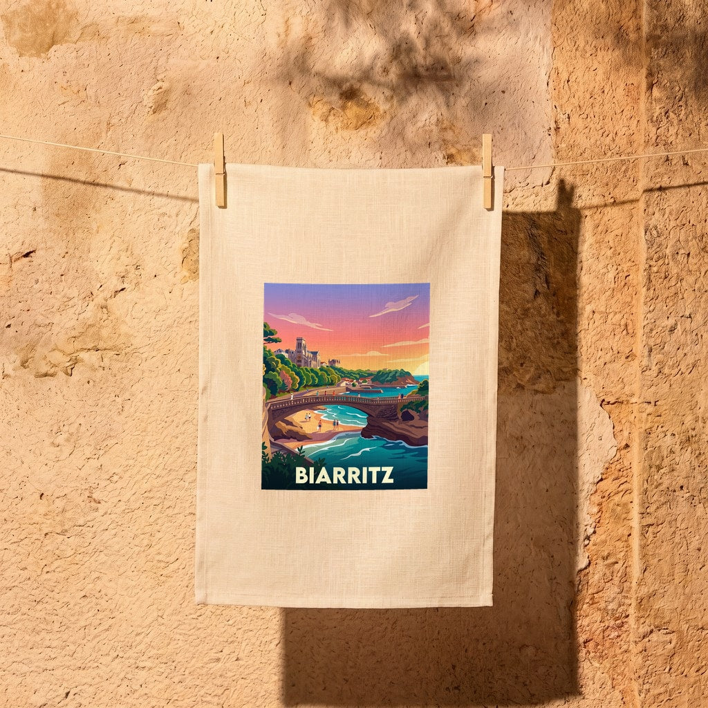 Torchon souvenir de la ville de Biarritz avec une illustration stylisée et colorée de son littoral au coucher du soleil.