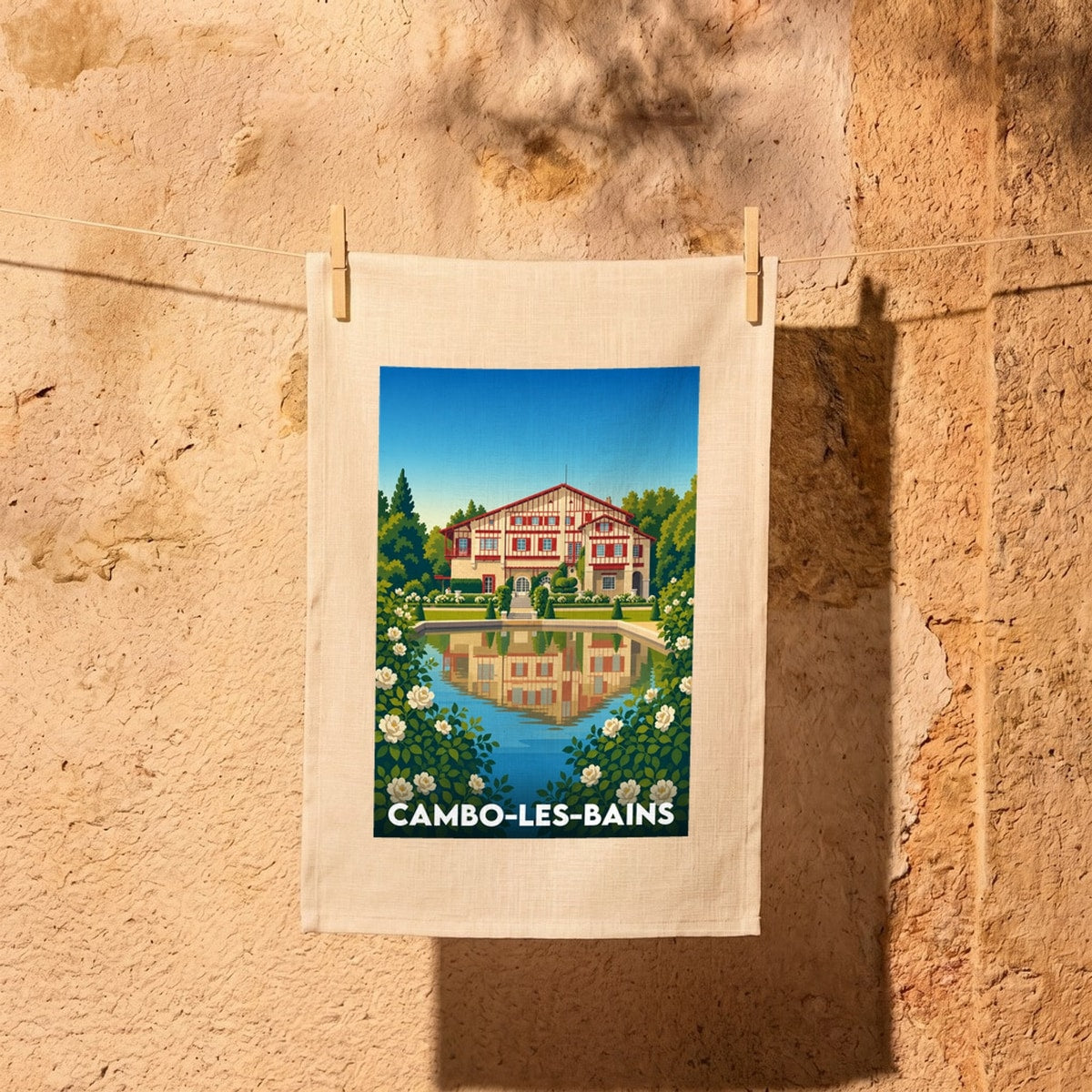 Torchon souvenir de la ville de Cambo-les-Bains orné d'une illustration stylisée de la Villa Arnaga et son jardin.