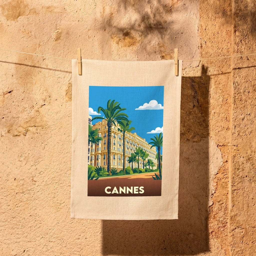 Torchon souvenir de la ville de Cannes avec une illustration stylisée représentant un palace et des palmiers.