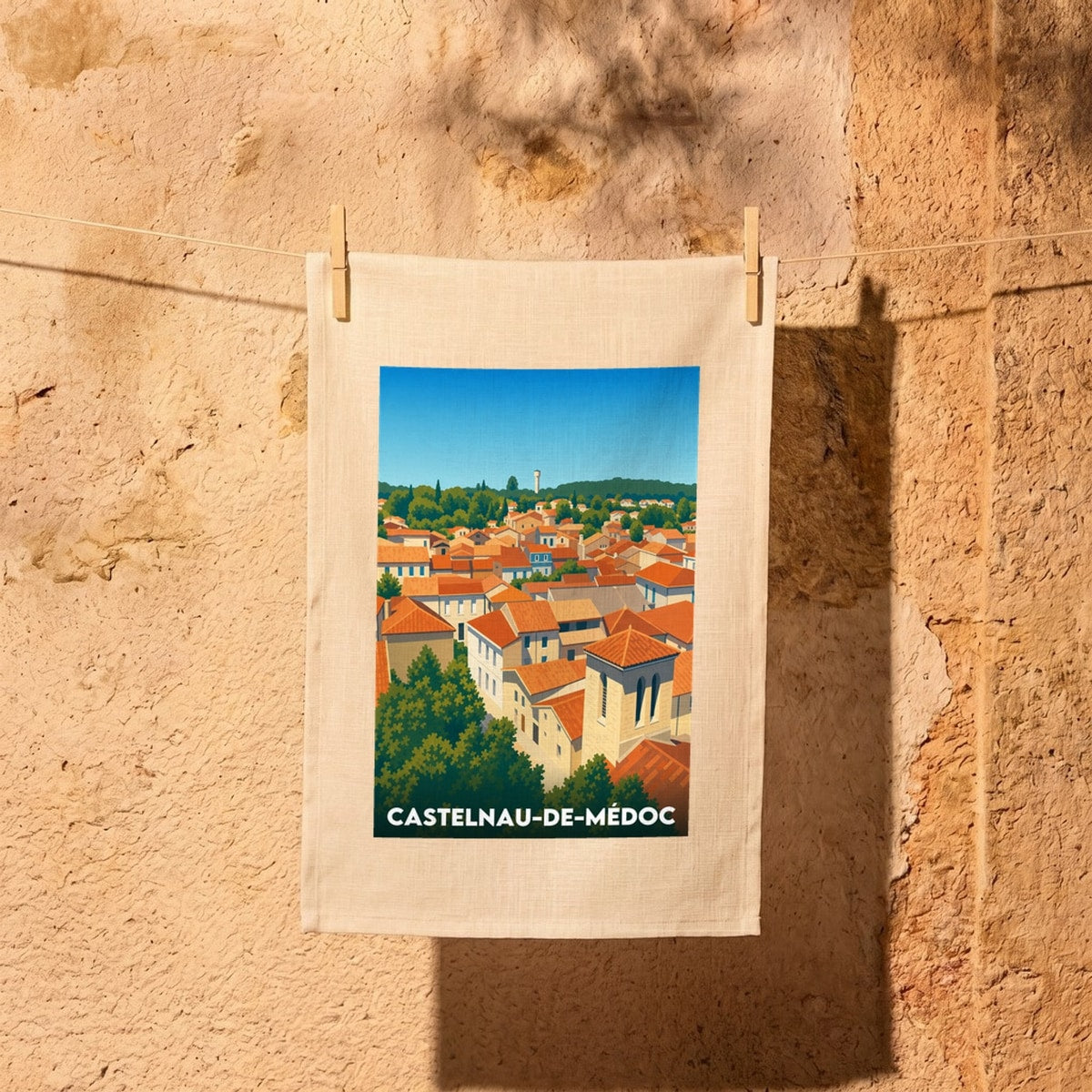 Torchon souvenir de Castelnau-de-Médoc avec une illustration stylisée des toits de la ville.