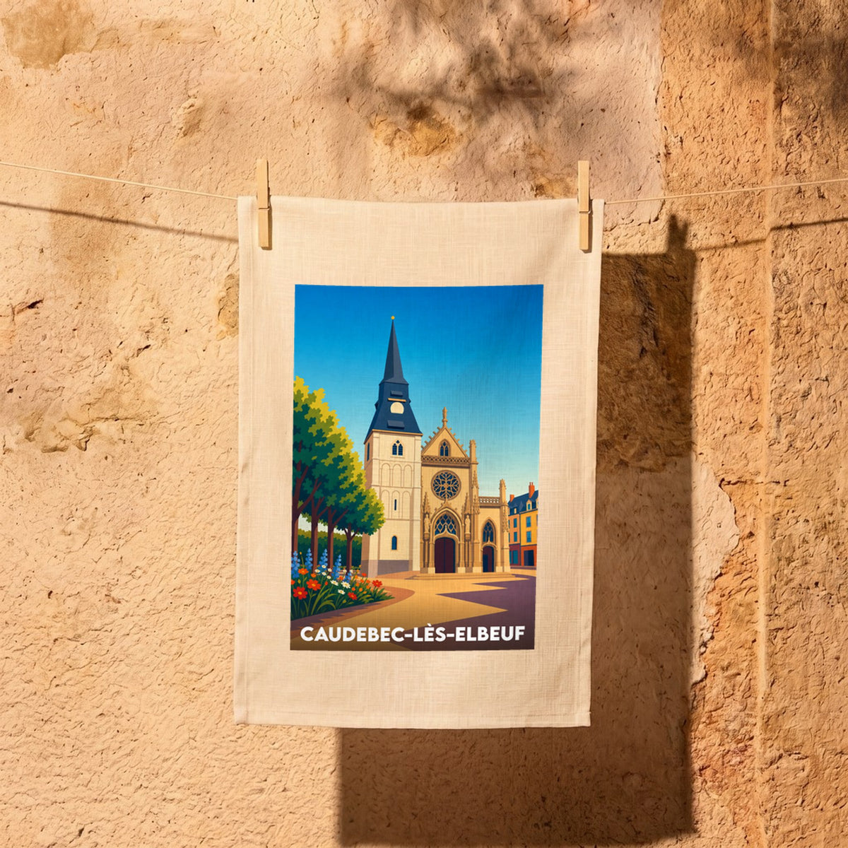 Torchon souvenir de la ville de Caudebec-lès-Elbeuf avec une illustration stylisée de son église et de ses maisons colorées.