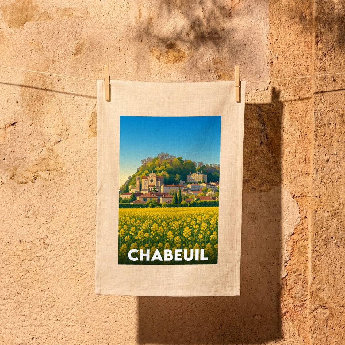 Torchon souvenir de la ville de Chabeuil illustrant son patrimoine historique au-dessus d'un champ de fleurs jaunes.
