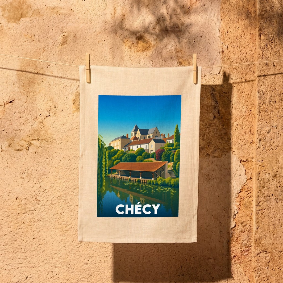 Torchon souvenir de la ville de Chécy illustré d'une vue stylisée du bord de Loire et de son église.