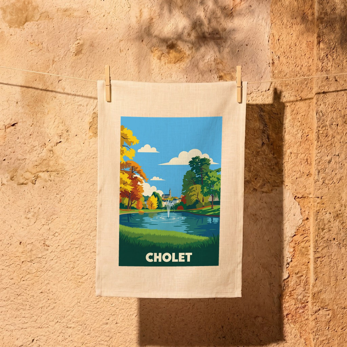 Torchon souvenir de la ville de Cholet avec une illustration stylisée d'un parc et d'une fontaine.