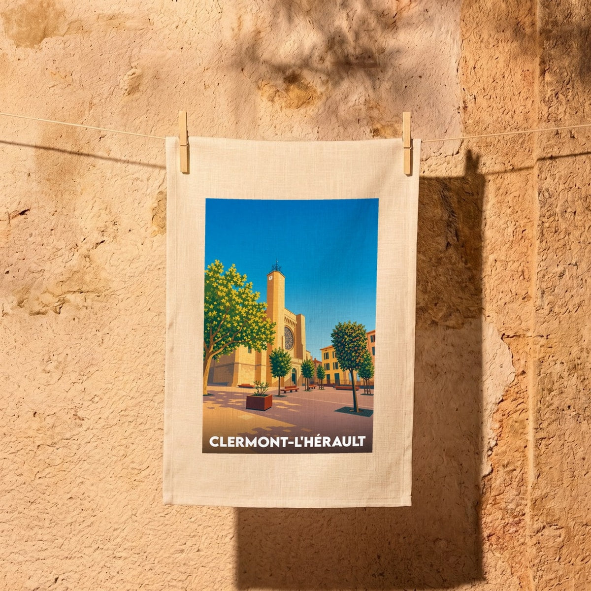 Torchon souvenir de la ville de Clermont-l'Hérault avec une illustration stylisée de sa place et de son église.