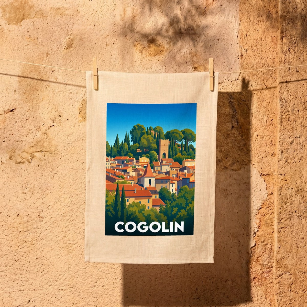 Torchon souvenir de la ville de Cogolin présentant une illustration stylisée et colorée de ses paysages provençaux.