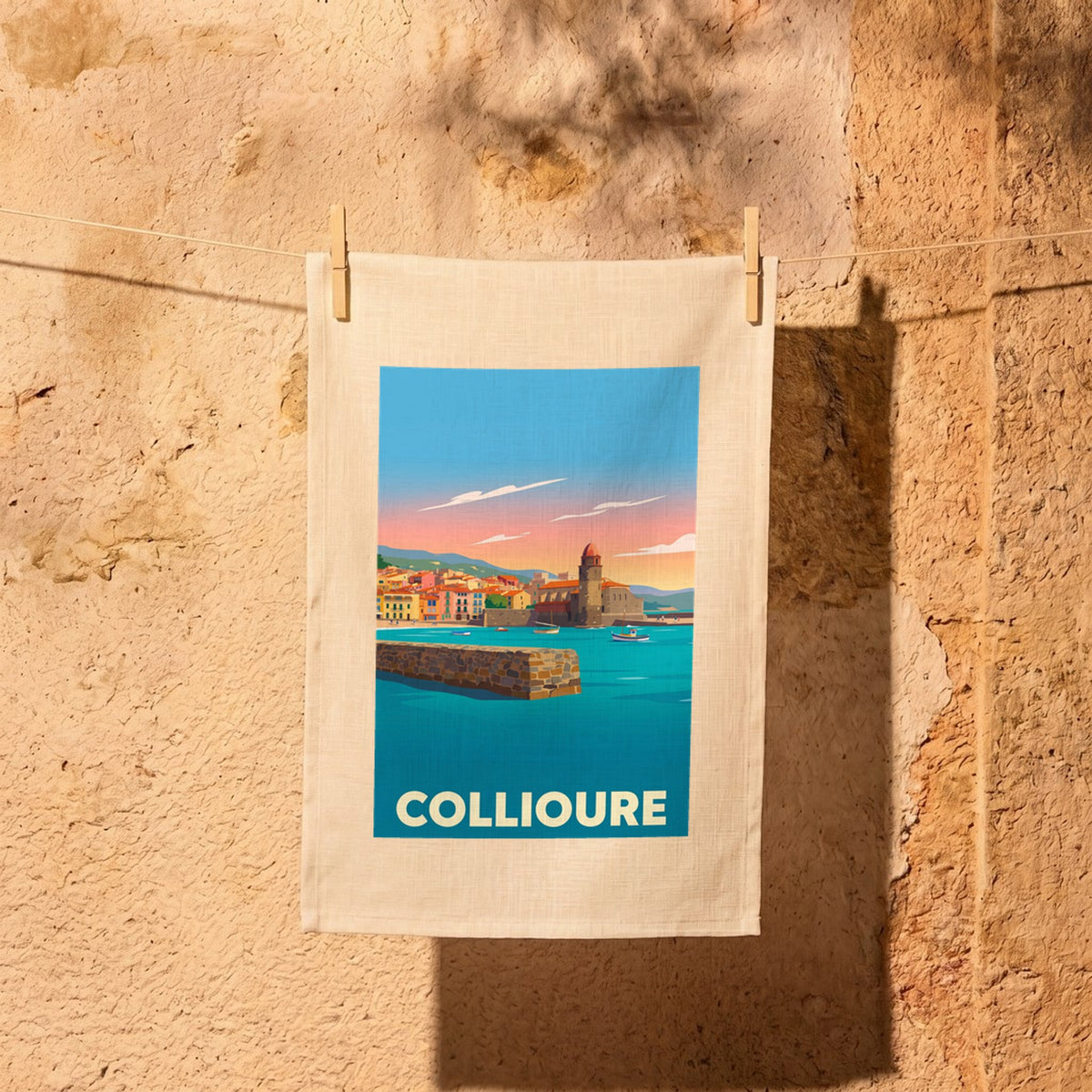 Torchon souvenir de la ville de Collioure avec une illustration stylisée et colorée de son front de mer au coucher du soleil.