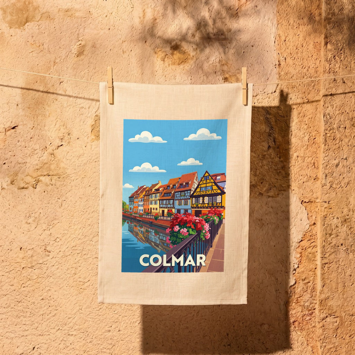 Torchon souvenir de la ville de Colmar avec une illustration stylisée de ses maisons colorées au bord de l'eau.
