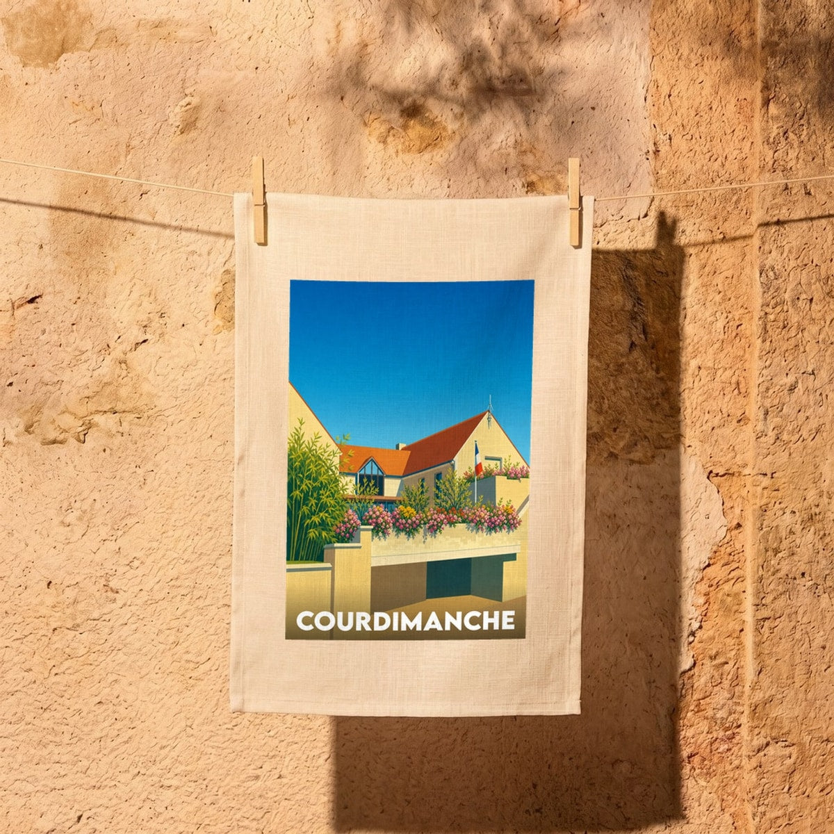 Torchon souvenir de la ville de Courdimanche illustré d'un bâtiment fleuri sous un ciel azur.