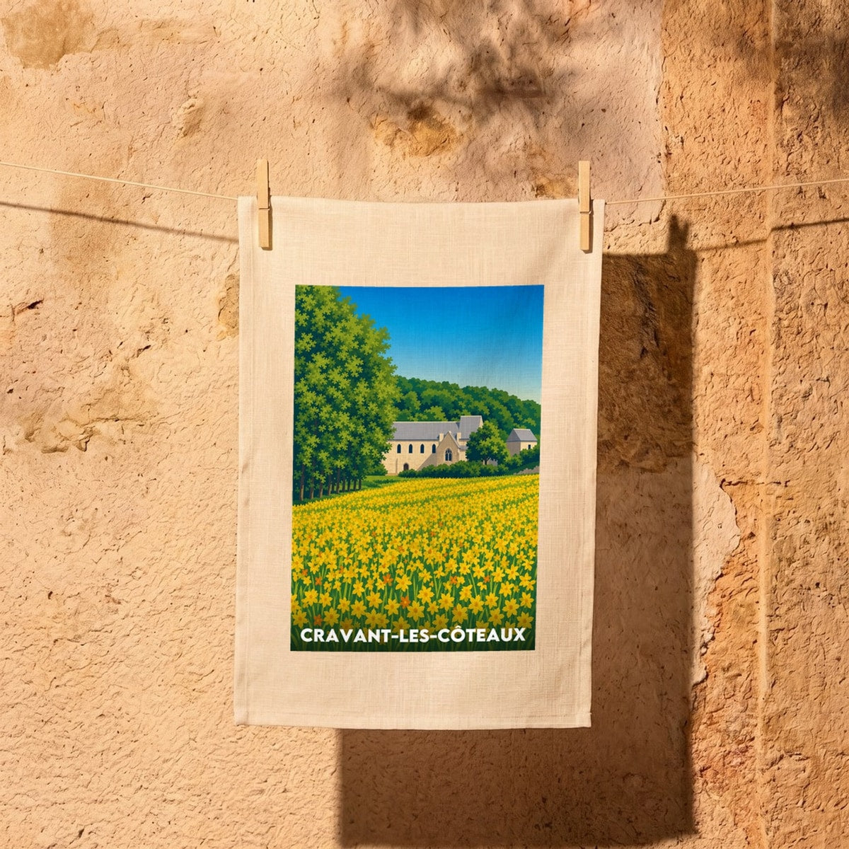 Torchon souvenir de la ville de Cravant-les-Côteaux avec une illustration stylisée d'un champ de fleurs jaunes et de son église.