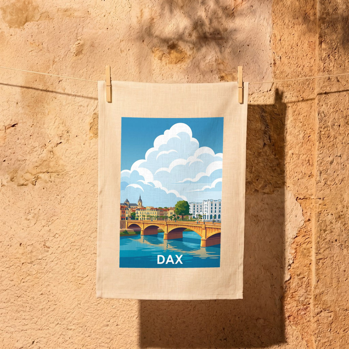 Torchon souvenir de la ville de Dax avec une illustration stylisée de son pont et de ses bâtiments.