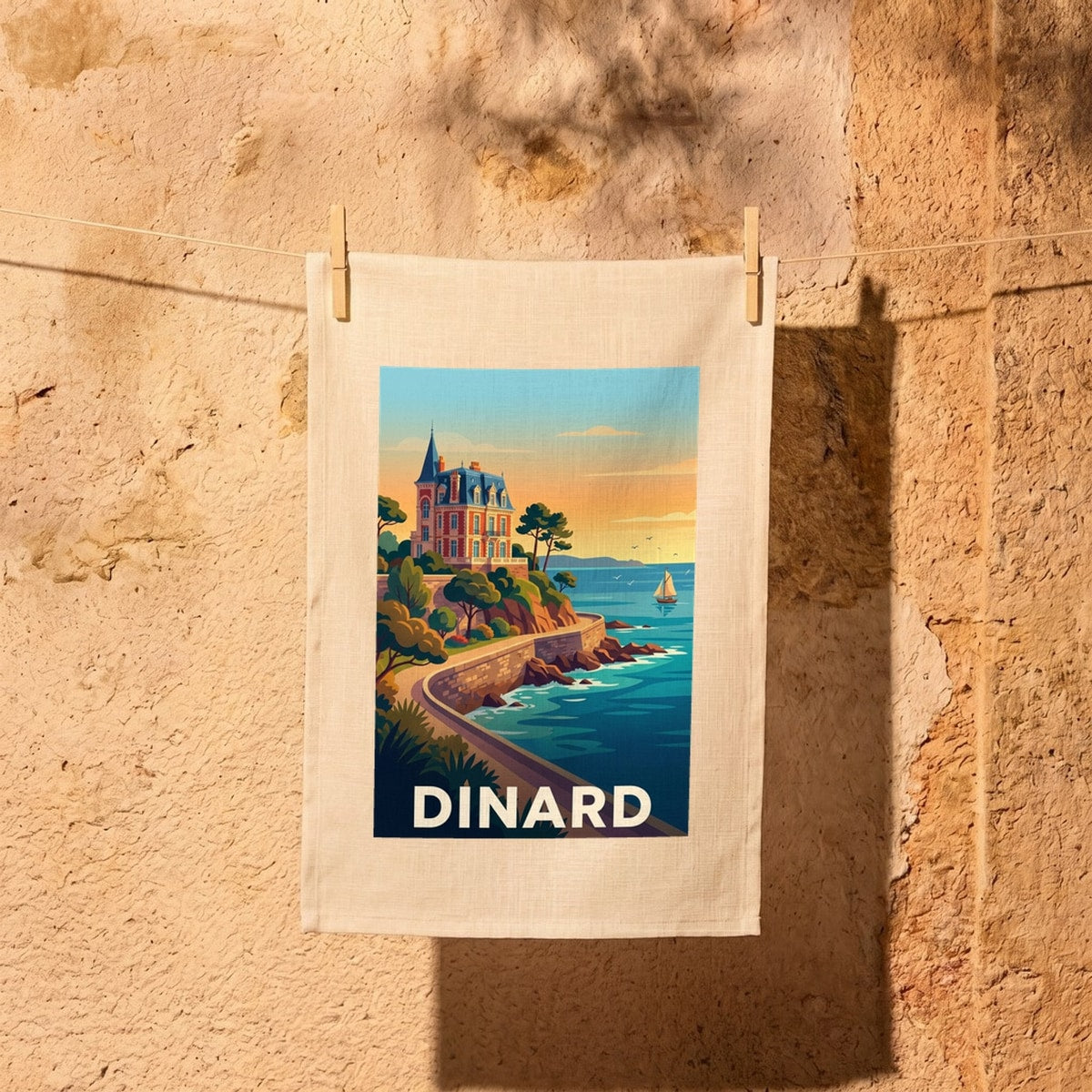 Torchon souvenir de la ville de Dinard avec une illustration stylisée d'une villa en bord de mer.