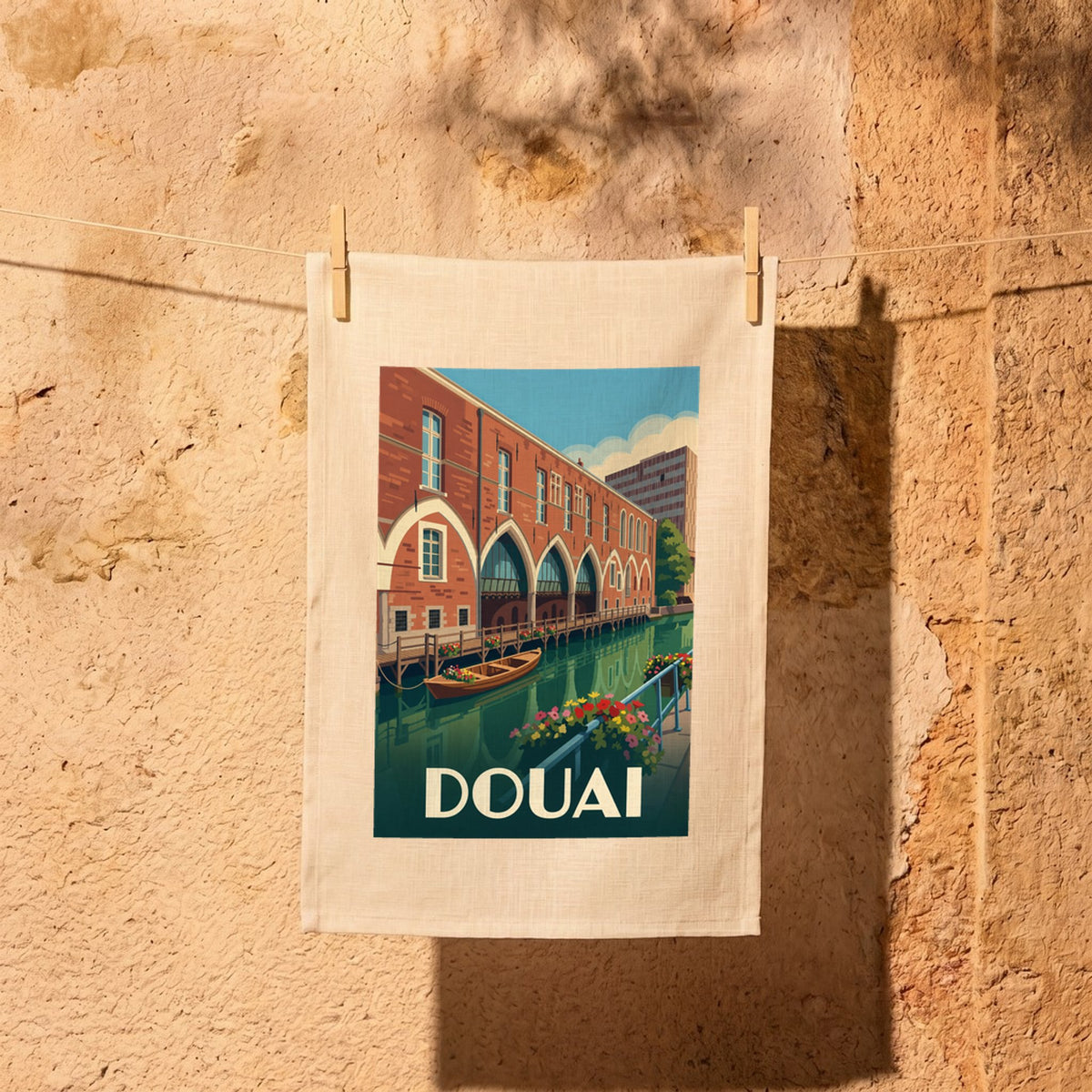 Torchon souvenir de la ville de Douai avec une illustration stylisée d'un canal bordé de bâtiments en briques.