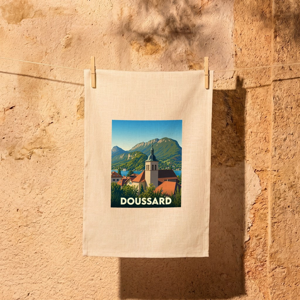 Torchon souvenir de la ville de Doussard avec une illustration stylisée de son église et des montagnes environnantes.