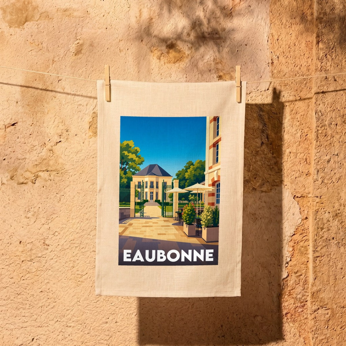 Torchon souvenir de la ville de Eaubonne illustrant une élégante bâtisse et une terrasse de café dans un style graphique épuré.