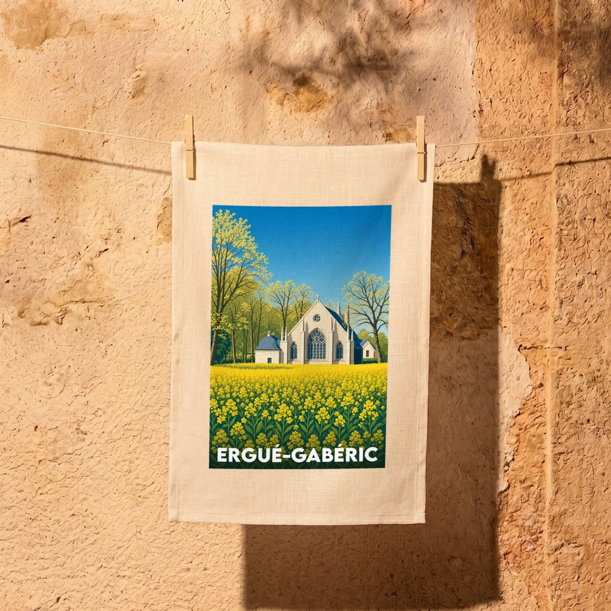 Torchon souvenir d'Ergué-Gabéric illustré d'une église blanche entourée d'un champ de fleurs jaunes.