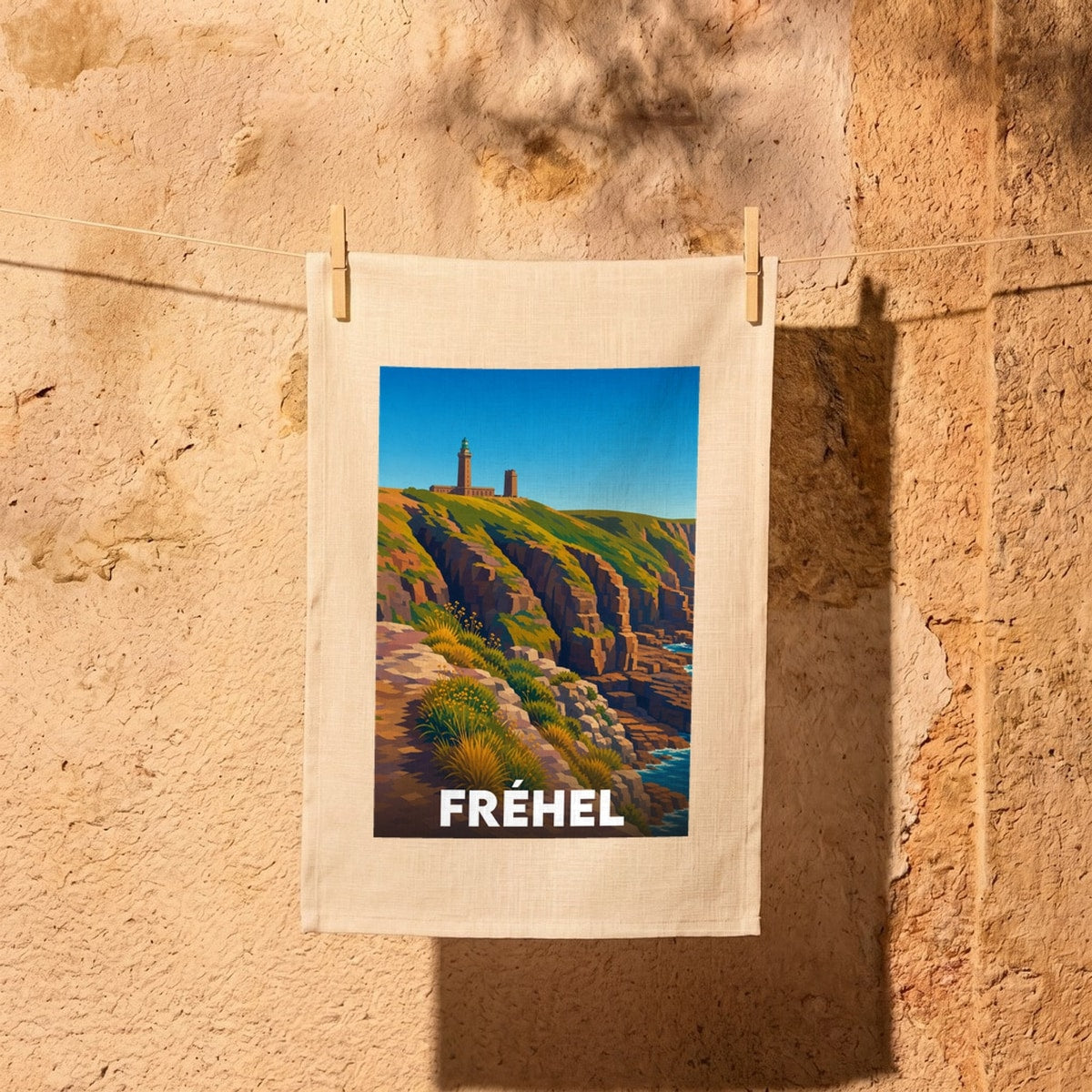 Torchon souvenir de la ville de Fréhel avec une illustration stylisée de ses falaises et de son phare.