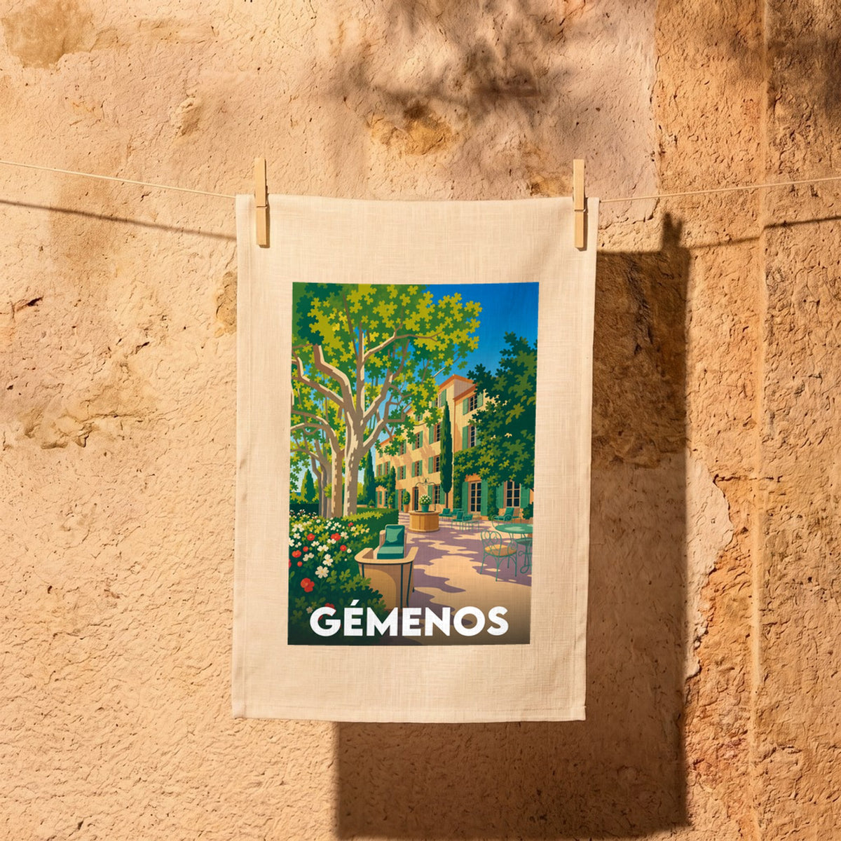 Torchon souvenir de la ville de Gémenos avec une illustration stylisée d'une bastide provençale.