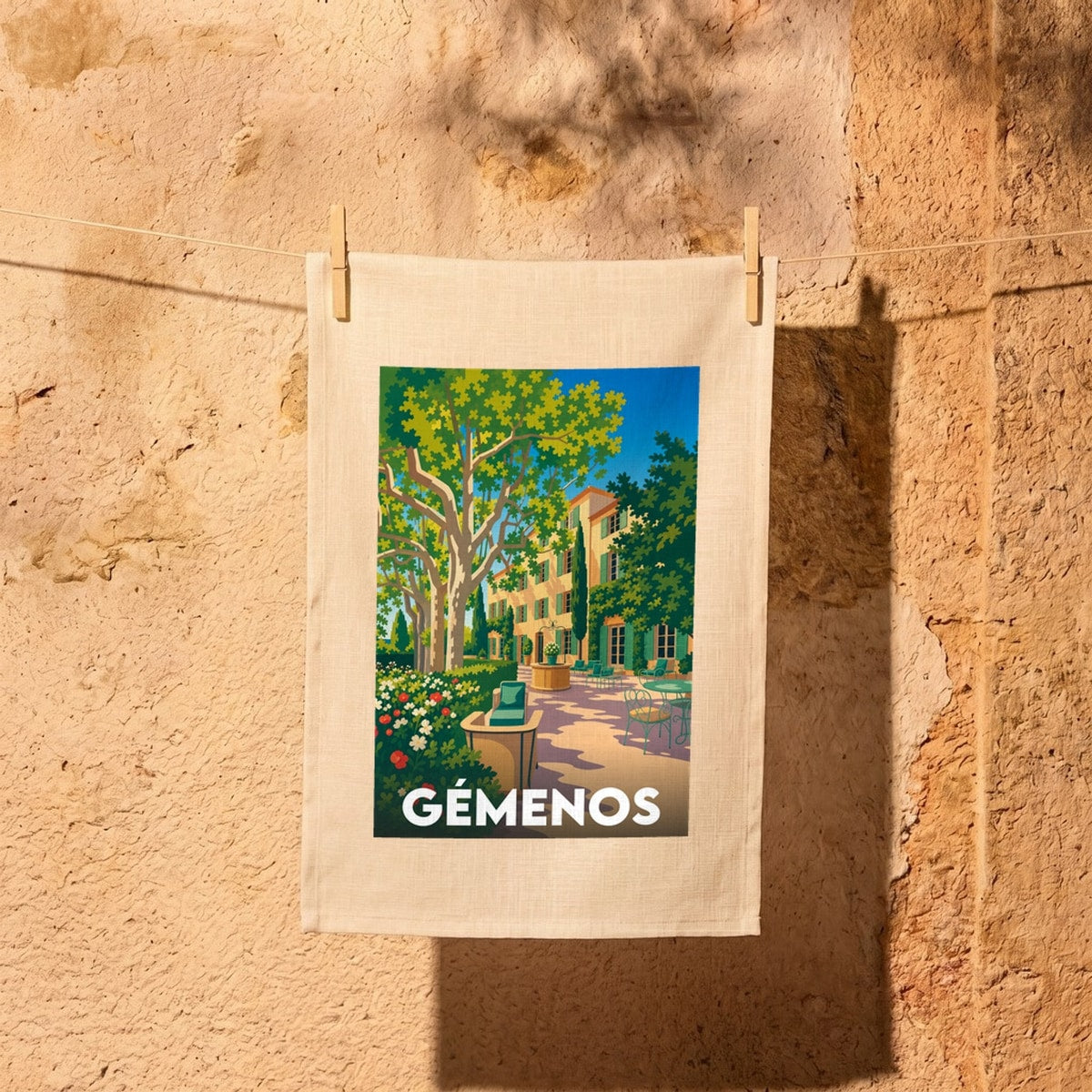Torchon souvenir de la ville de Gémenos avec une illustration stylisée d'une bastide provençale.