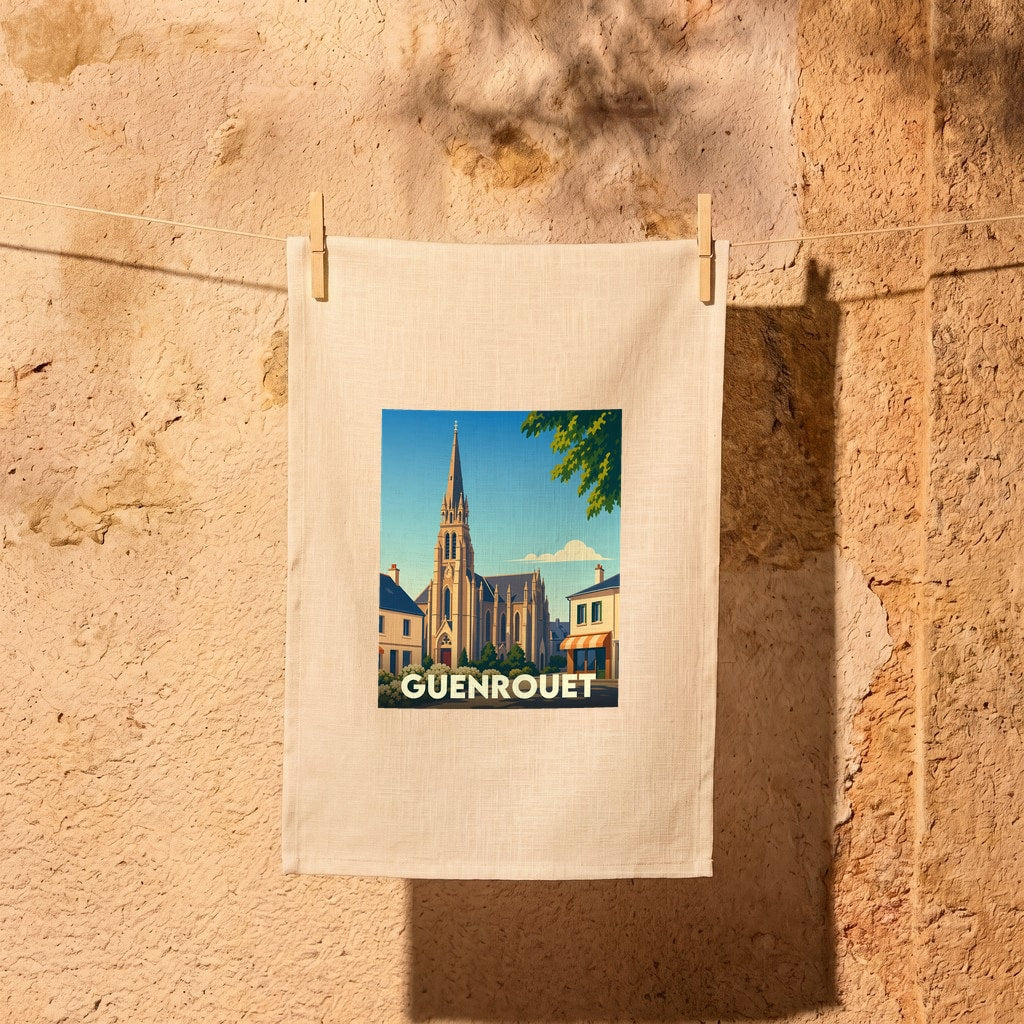 Torchon souvenir de la ville de Guenrouet illustré d'une vue stylisée de son église et suspendu devant un mur en pierre.