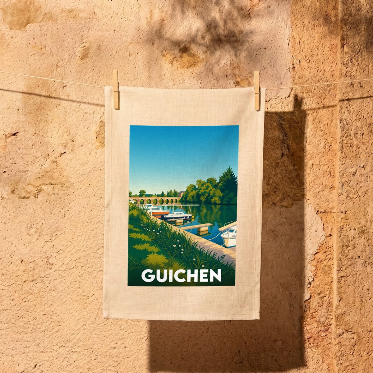 Torchon souvenir de la ville de Guichen illustré par une scène de port de plaisance stylisée.