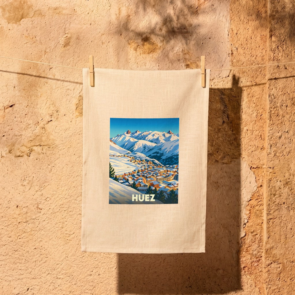 Torchon souvenir de la ville de Huez avec une illustration stylisée d'un village de montagne enneigé.