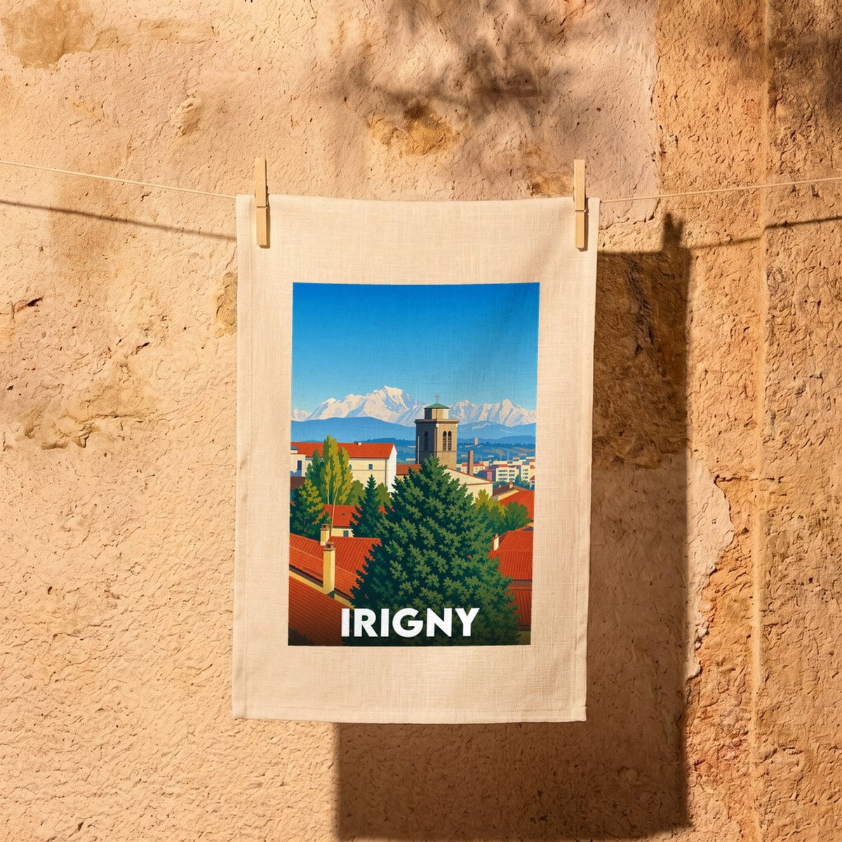 Torchon souvenir de la ville d'Irigny avec une illustration stylisée représentant ses toits rouges et les Alpes en arrière-plan.