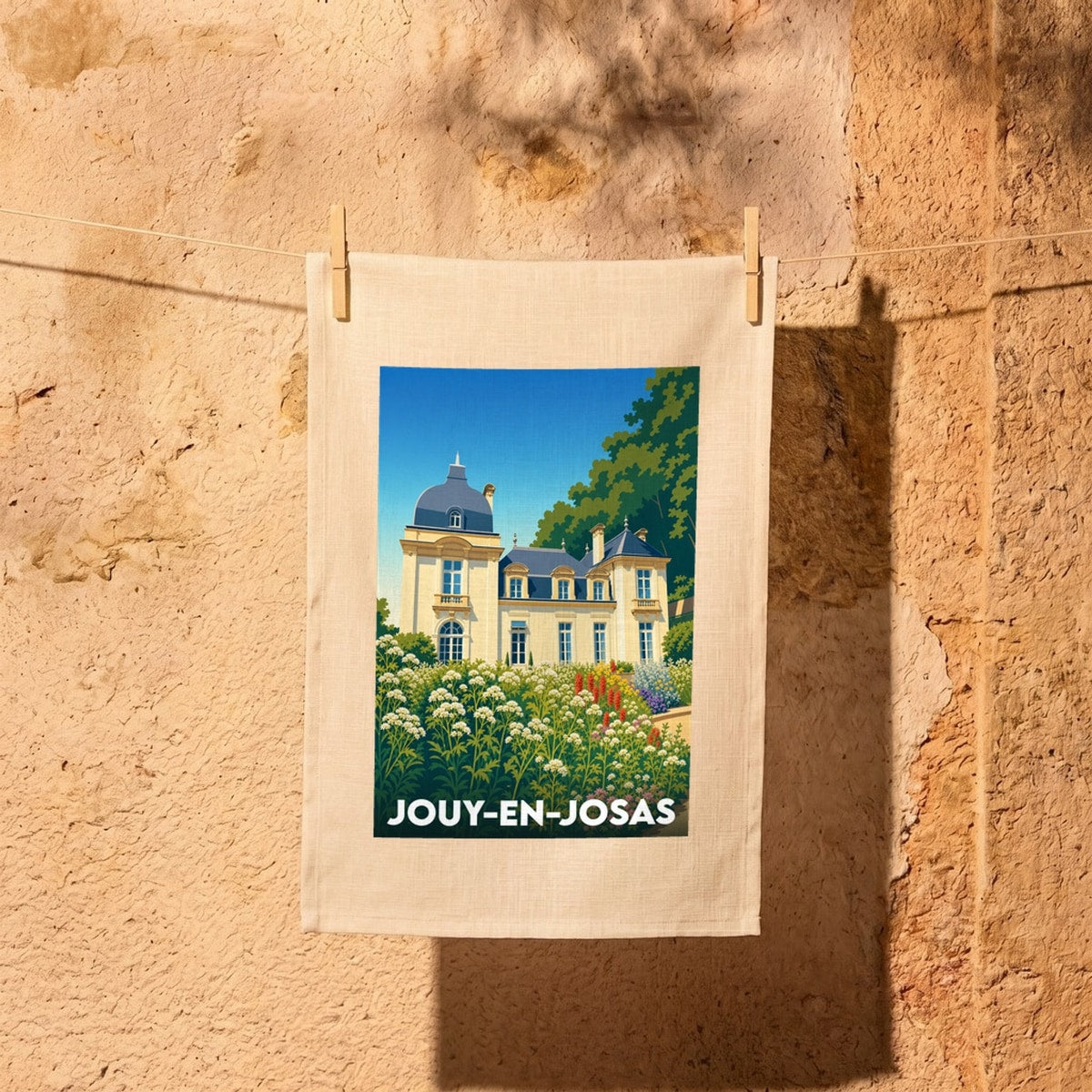 Torchon souvenir de la ville de Jouy-en-Josas illustré par un château entouré de fleurs.