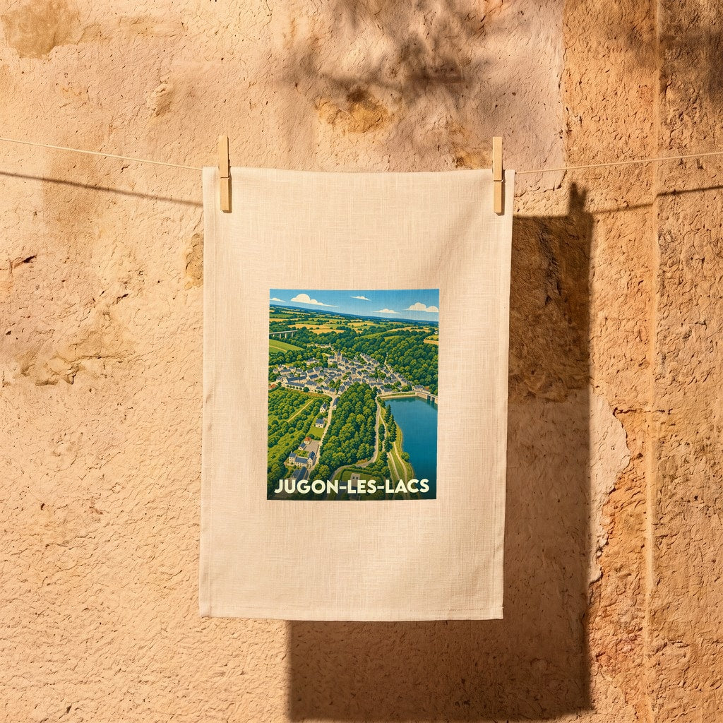 Torchon souvenir de la ville de Jugon-les-Lacs avec une illustration de style affiche vintage représentant un paysage de vallée.
