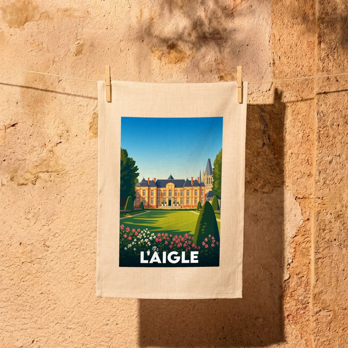 Torchon souvenir de la ville de L'Aigle avec une illustration stylisée de son château et de ses jardins.