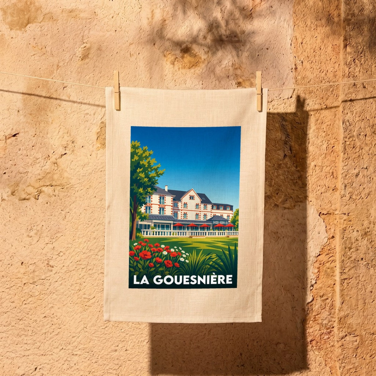 Torchon souvenir de la ville de La Gouesnière avec une illustration stylisée d'une grande demeure.