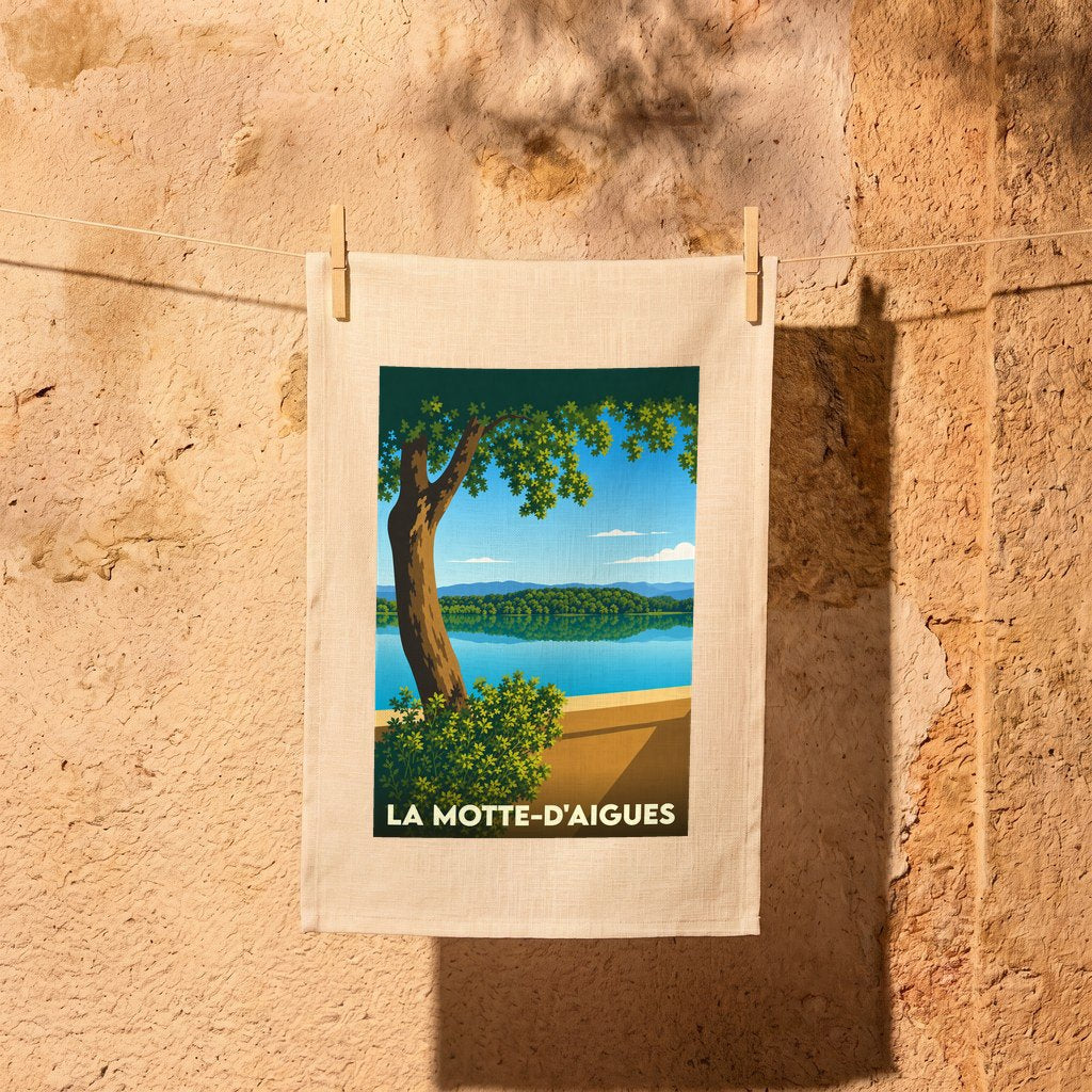 Torchon souvenir de la ville de La Motte-d'Aigues avec une illustration stylisée d'un paysage lacustre.