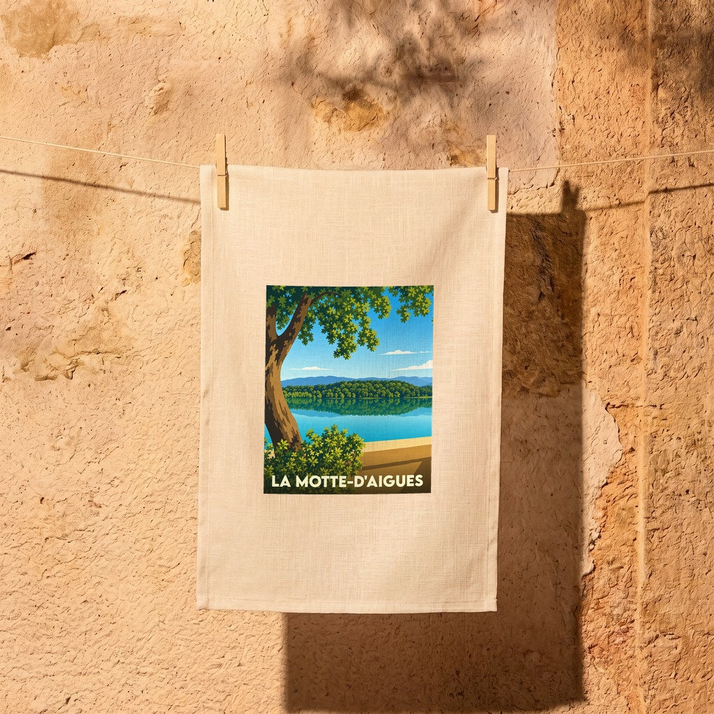 Torchon souvenir de la ville de La Motte-d'Aigues avec une illustration stylisée d'un paysage lacustre.