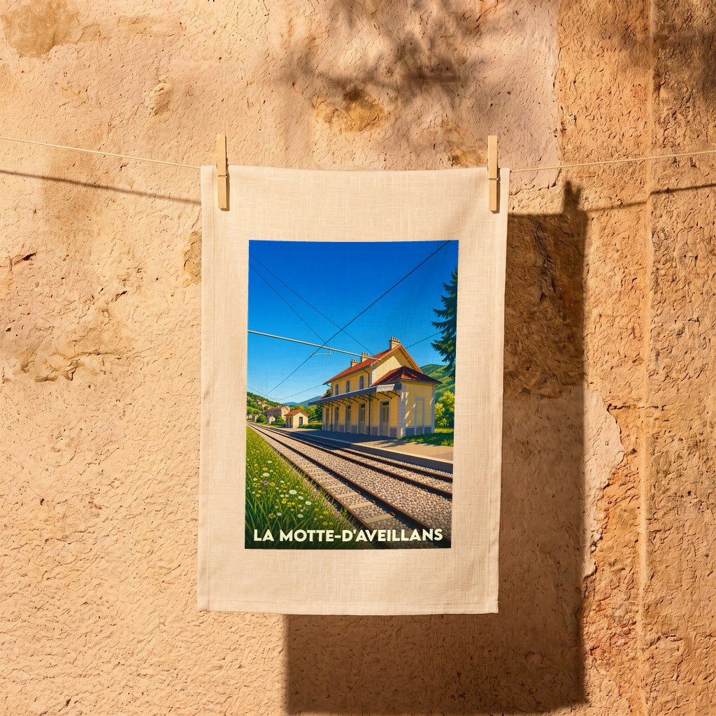 Torchon souvenir de la ville de La Motte-d'Aveillans illustré d'une gare sous un ciel bleu.