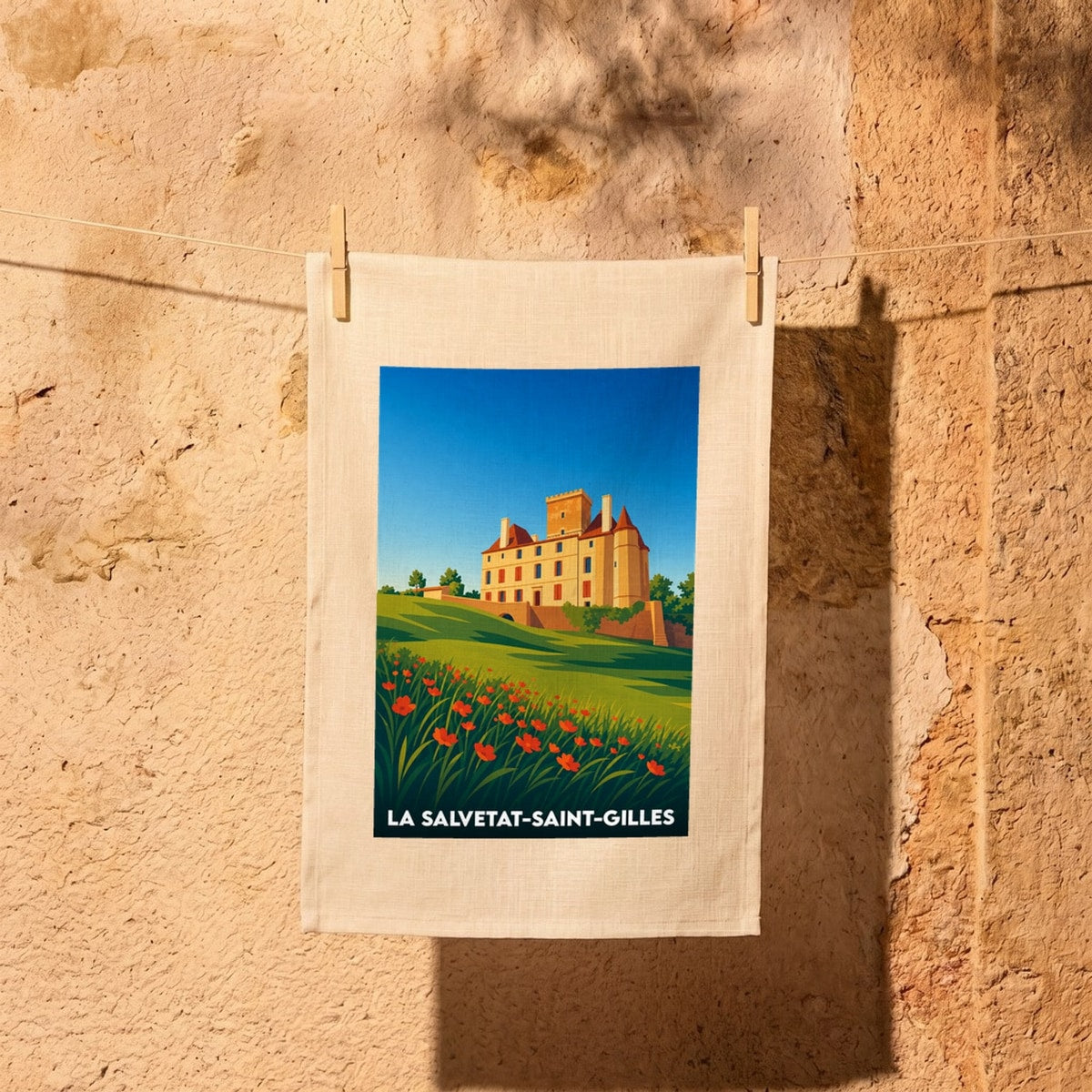 Torchon souvenir de la ville de La Salvetat-Saint-Gilles avec une illustration stylisée de son château et d'un champ de coquelicots.