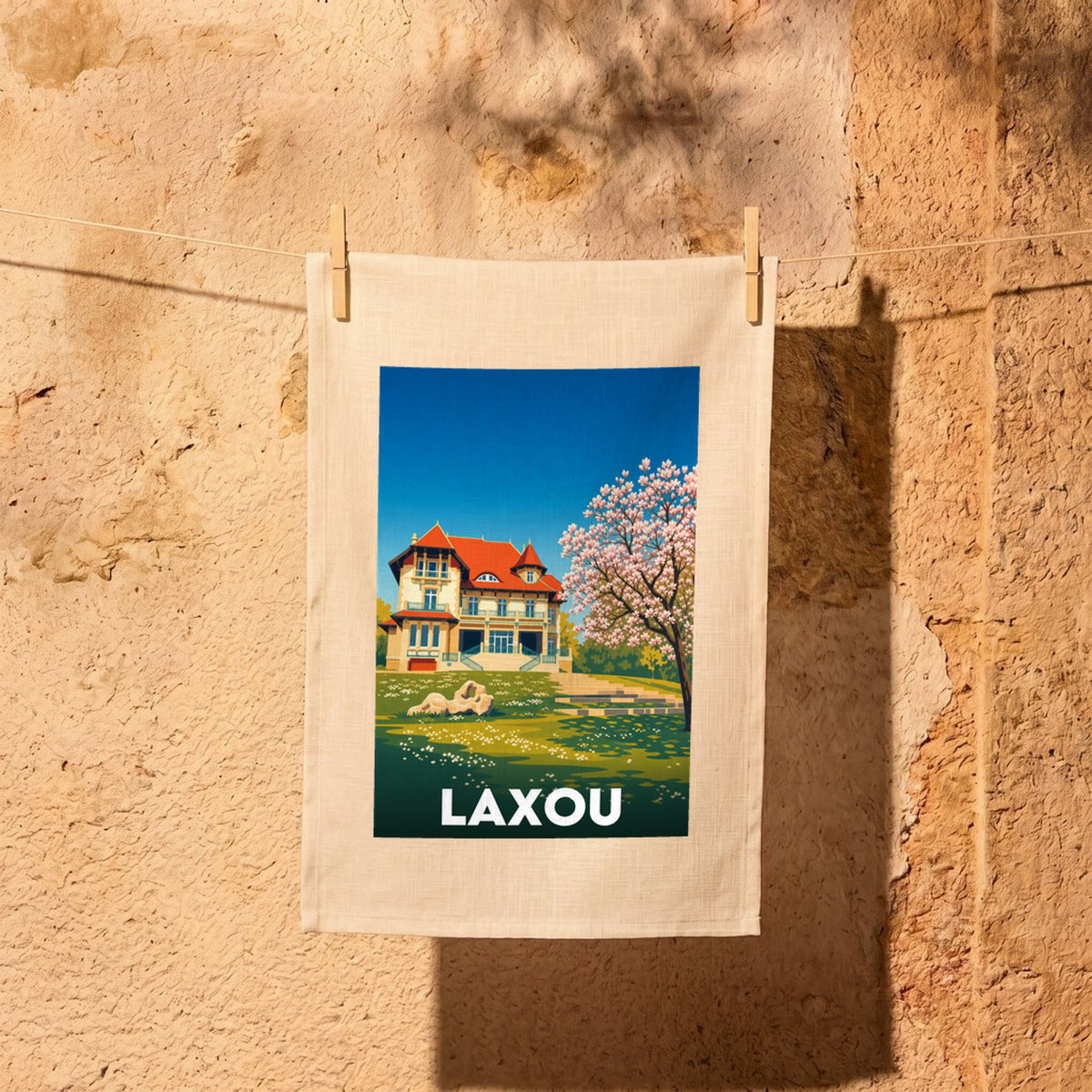 Torchon souvenir de la ville de Laxou avec une illustration colorée d'une villa et d'un arbre en fleurs.