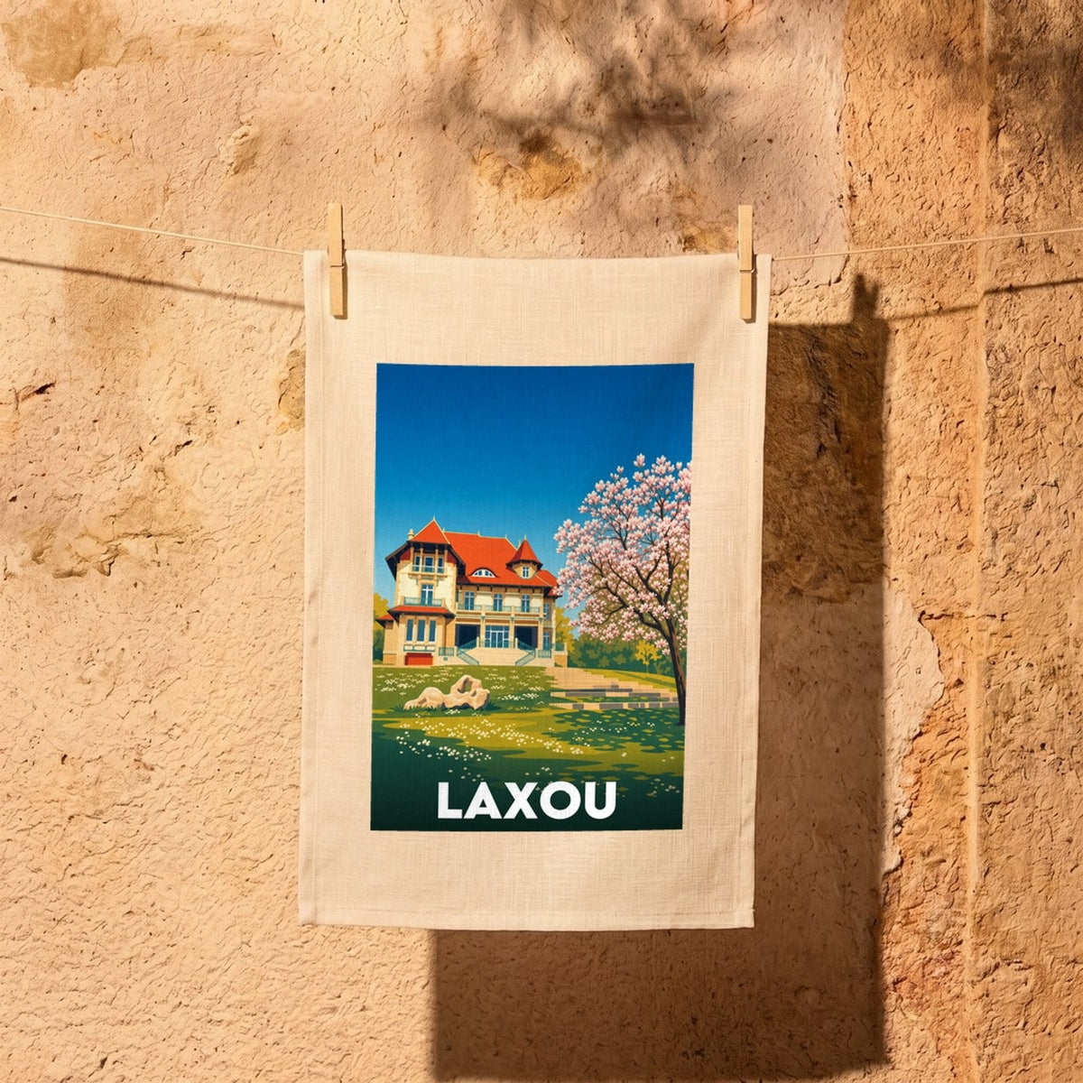 Torchon souvenir de la ville de Laxou avec une illustration colorée d'une villa et d'un arbre en fleurs.