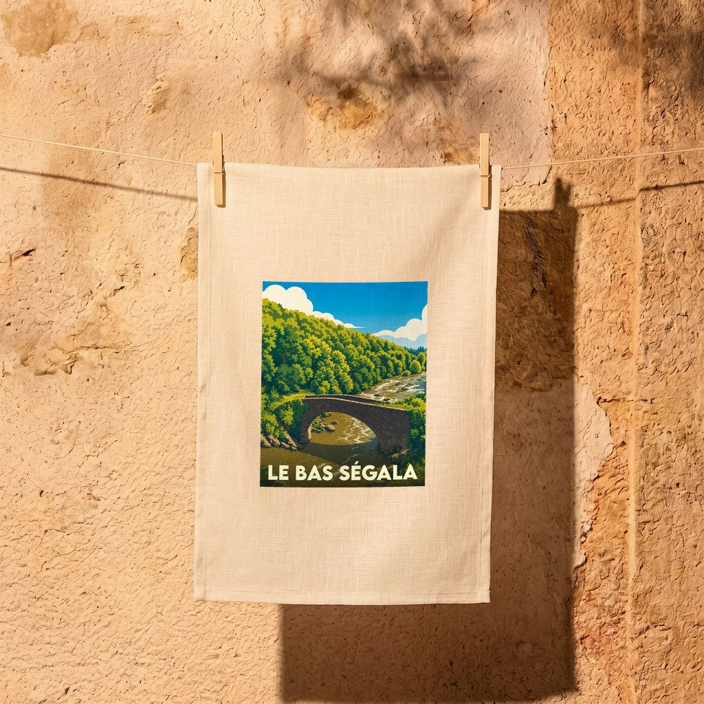 Torchon souvenir de la commune de Le Bas Ségala avec une illustration stylisée d'un pont en pierre dans une vallée boisée.