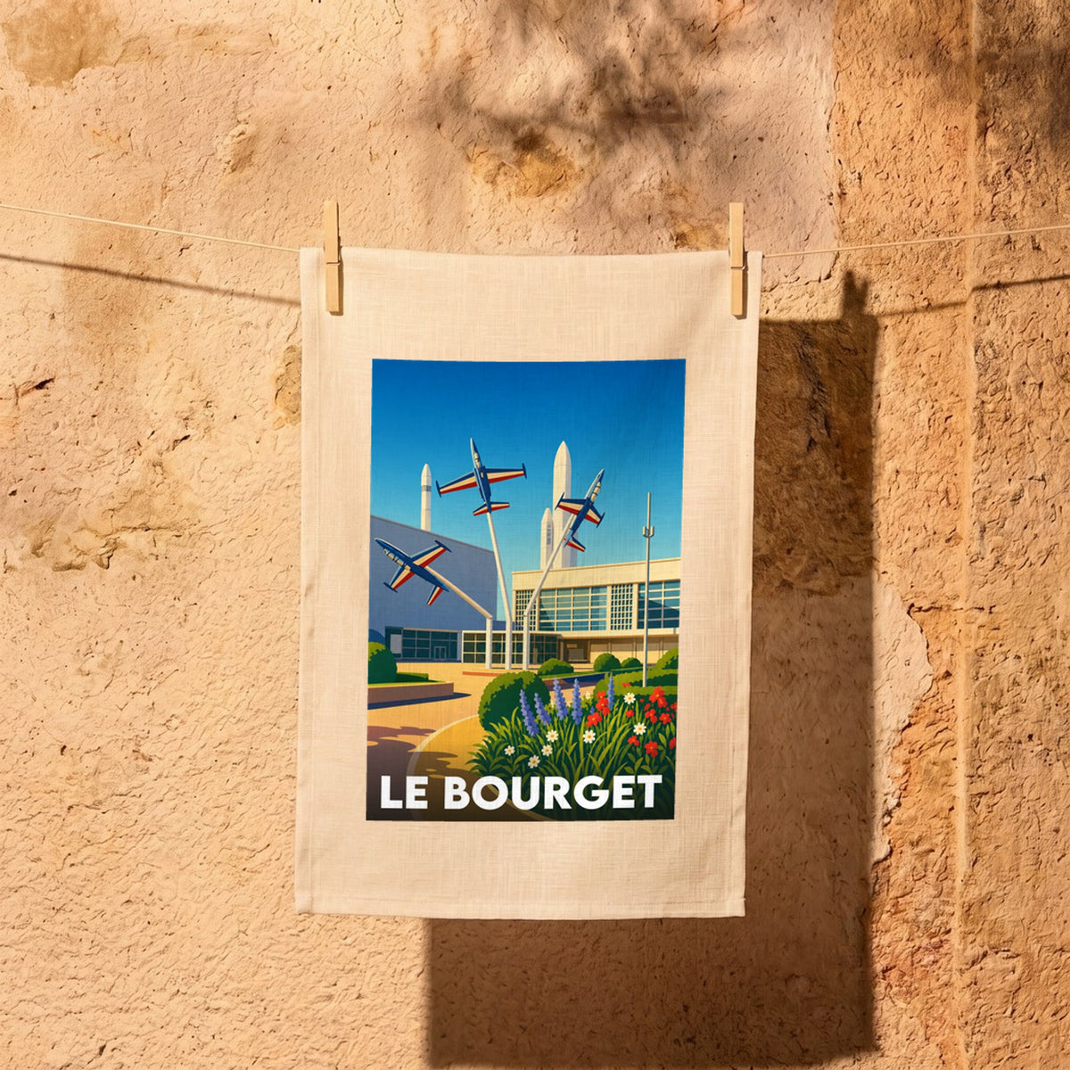 Torchon souvenir de la ville de Le Bourget avec une illustration stylisée d'avions et de fusées.