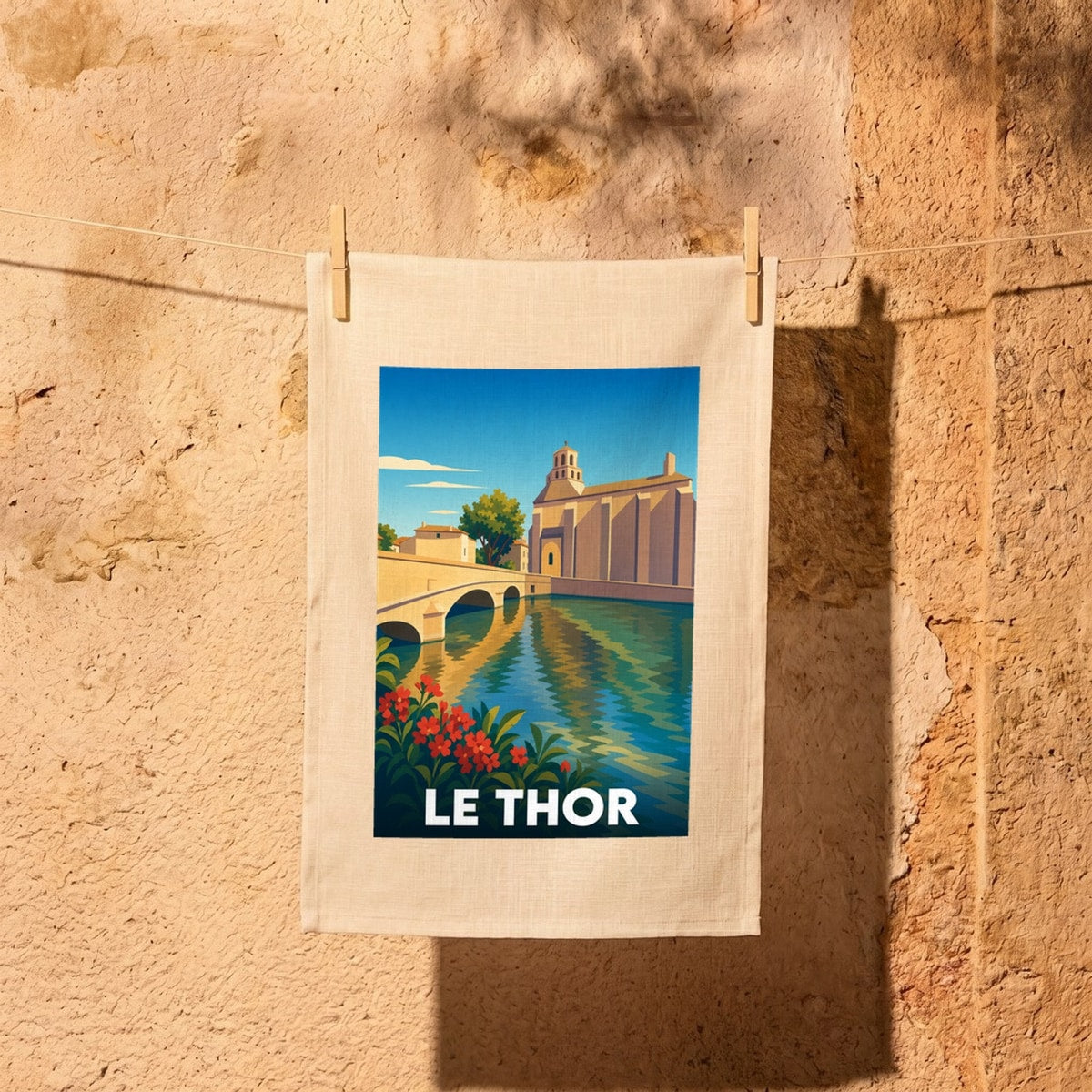Torchon souvenir de la ville de Le Thor illustrant son pont et son église dans un style vintage.