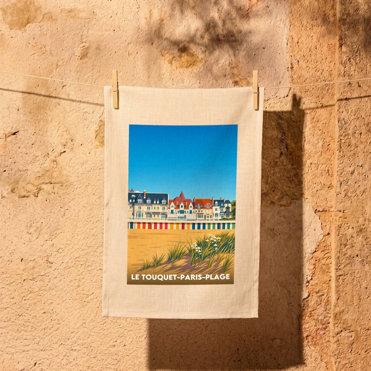 Torchon souvenir de la ville de Le Touquet-Paris-Plage avec une illustration stylisée de son front de mer et de ses cabines colorées.
