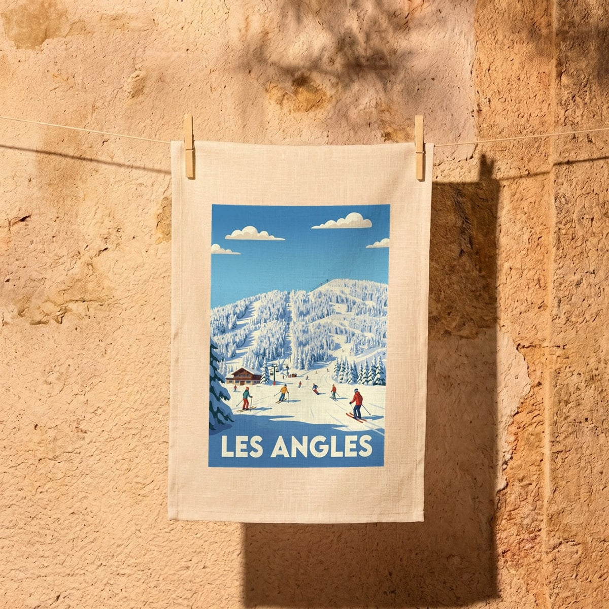 Torchon souvenir de la ville de Les Angles orné d'une illustration stylisée de station de ski.