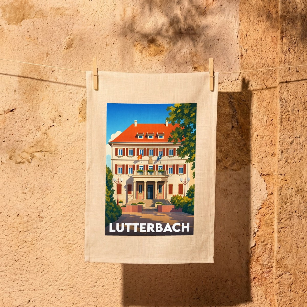Torchon souvenir de la ville de Lutterbach illustré d'un bâtiment de style néoclassique sous un ciel bleu.