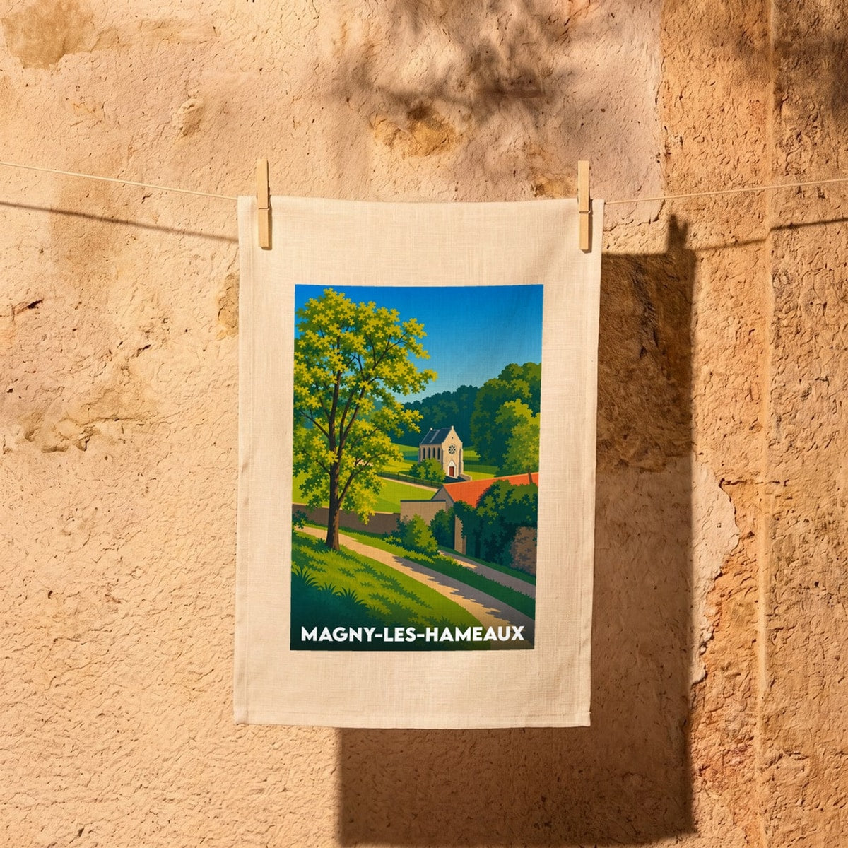 Torchon souvenir de la ville de Magny-les-Hameaux avec une illustration stylisée d'un paysage rural.
