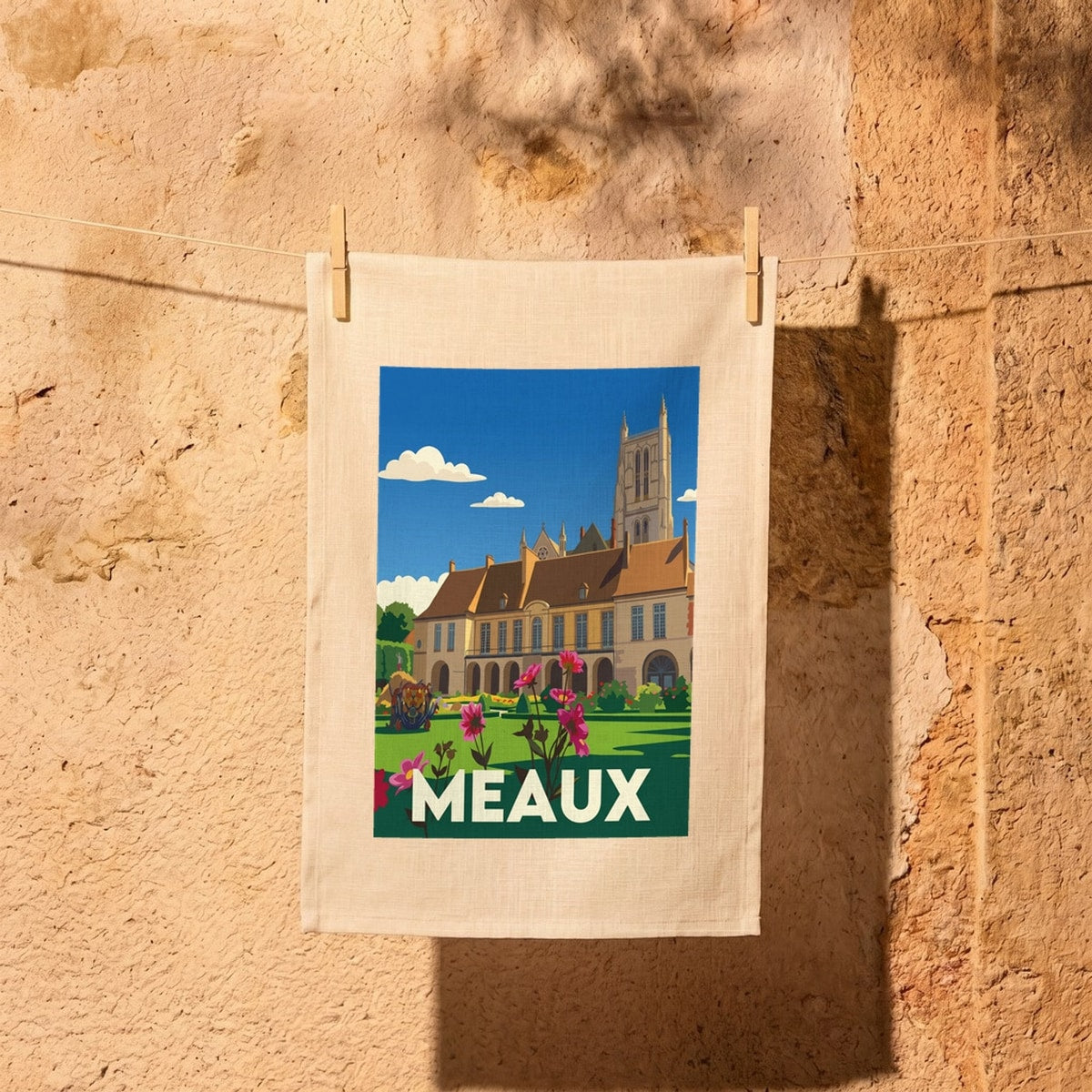 Torchon souvenir de la ville de Meaux avec une illustration stylisée de ses monuments et jardins.