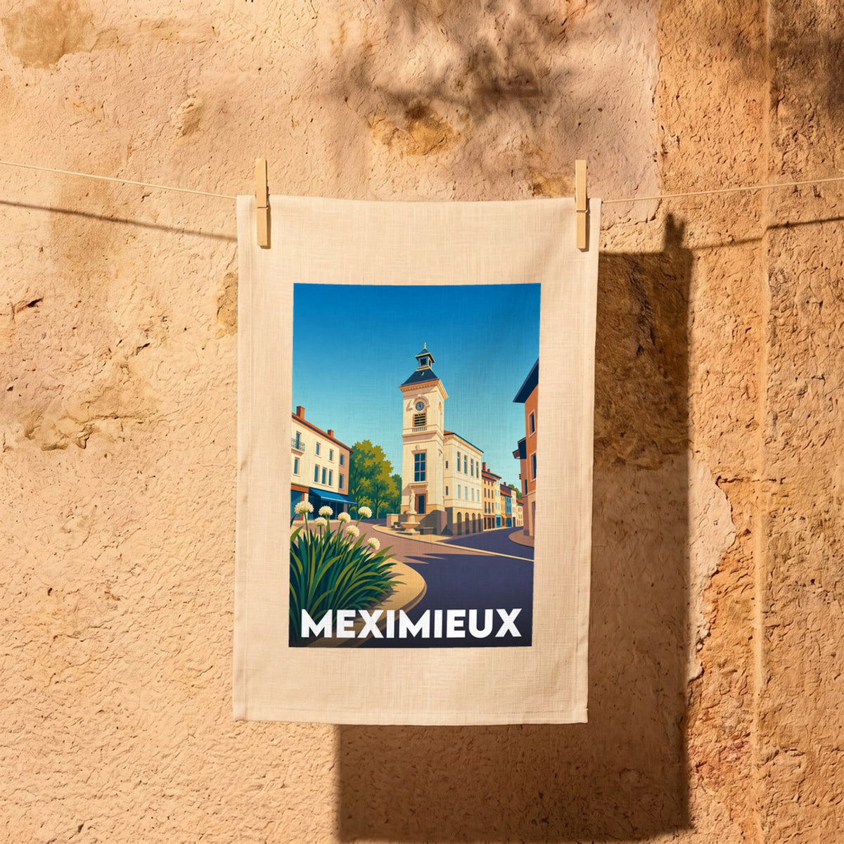 Torchon souvenir de la ville de Meximieux avec une illustration stylisée de sa place centrale.