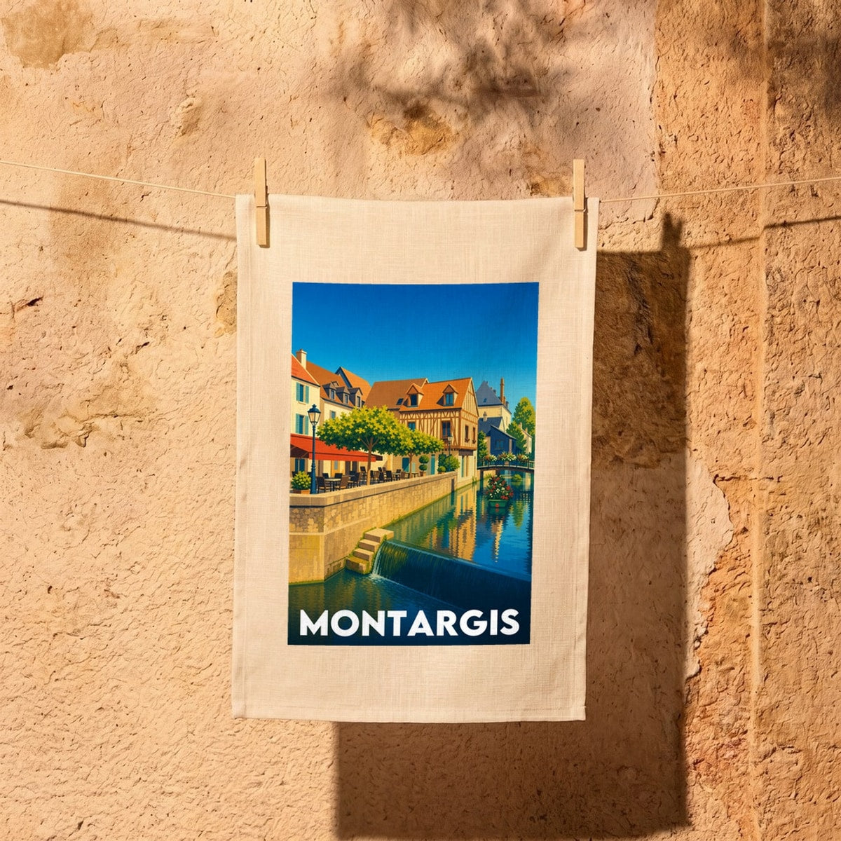 Torchon souvenir de la ville de Montargis avec une illustration stylisée d'un canal et de maisons à colombages.