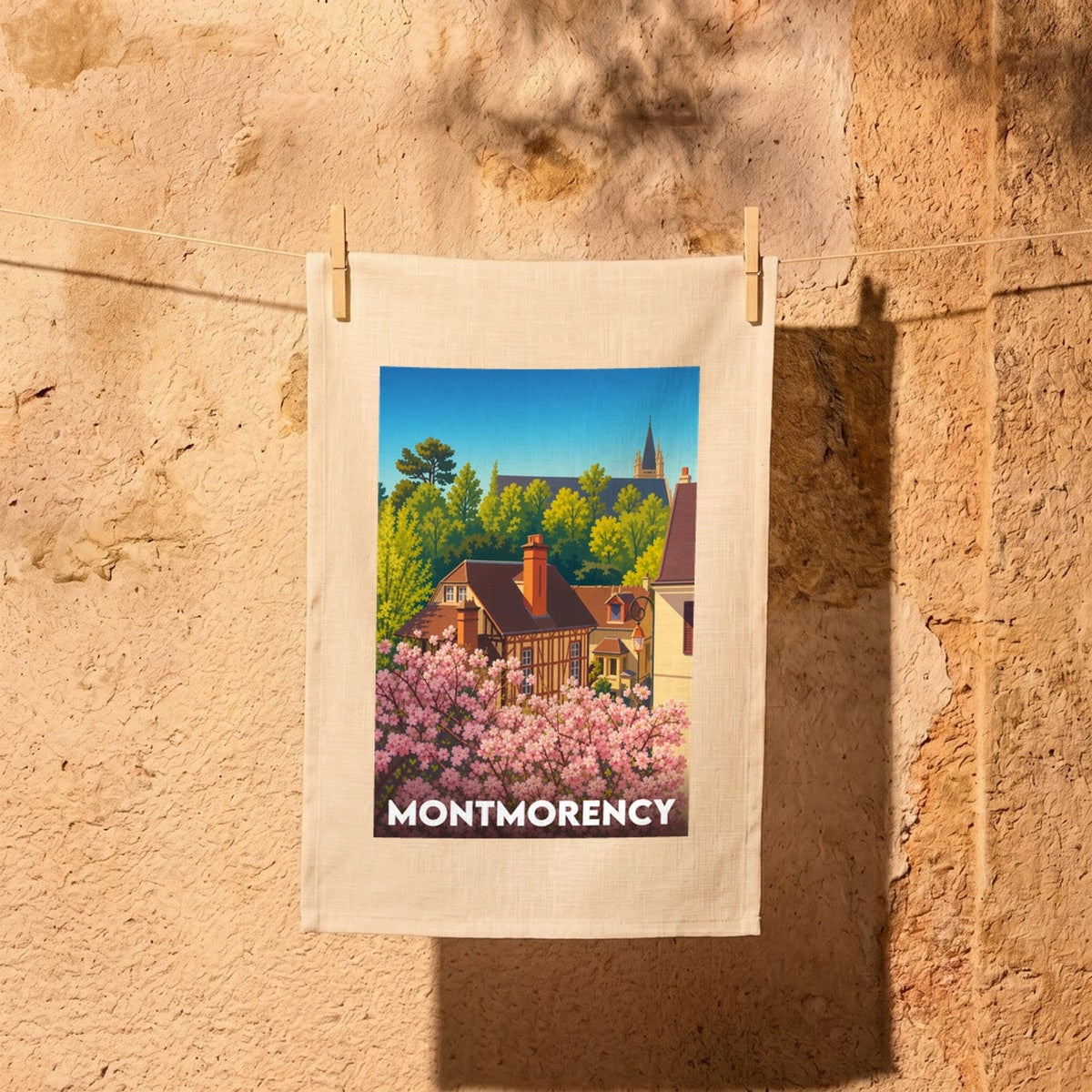 Torchon souvenir de la ville de Montmorency avec une illustration stylisée de maisons et de cerisiers en fleurs.