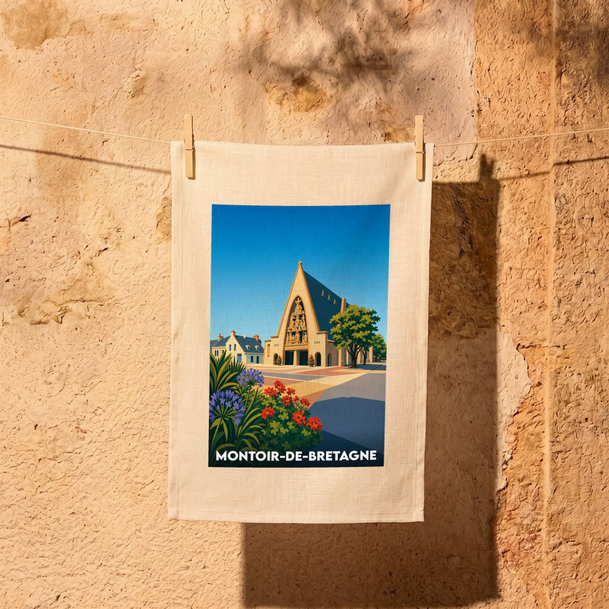 Torchon souvenir de la ville de Montoir-de-Bretagne avec une illustration stylisée de son église et de ses maisons.