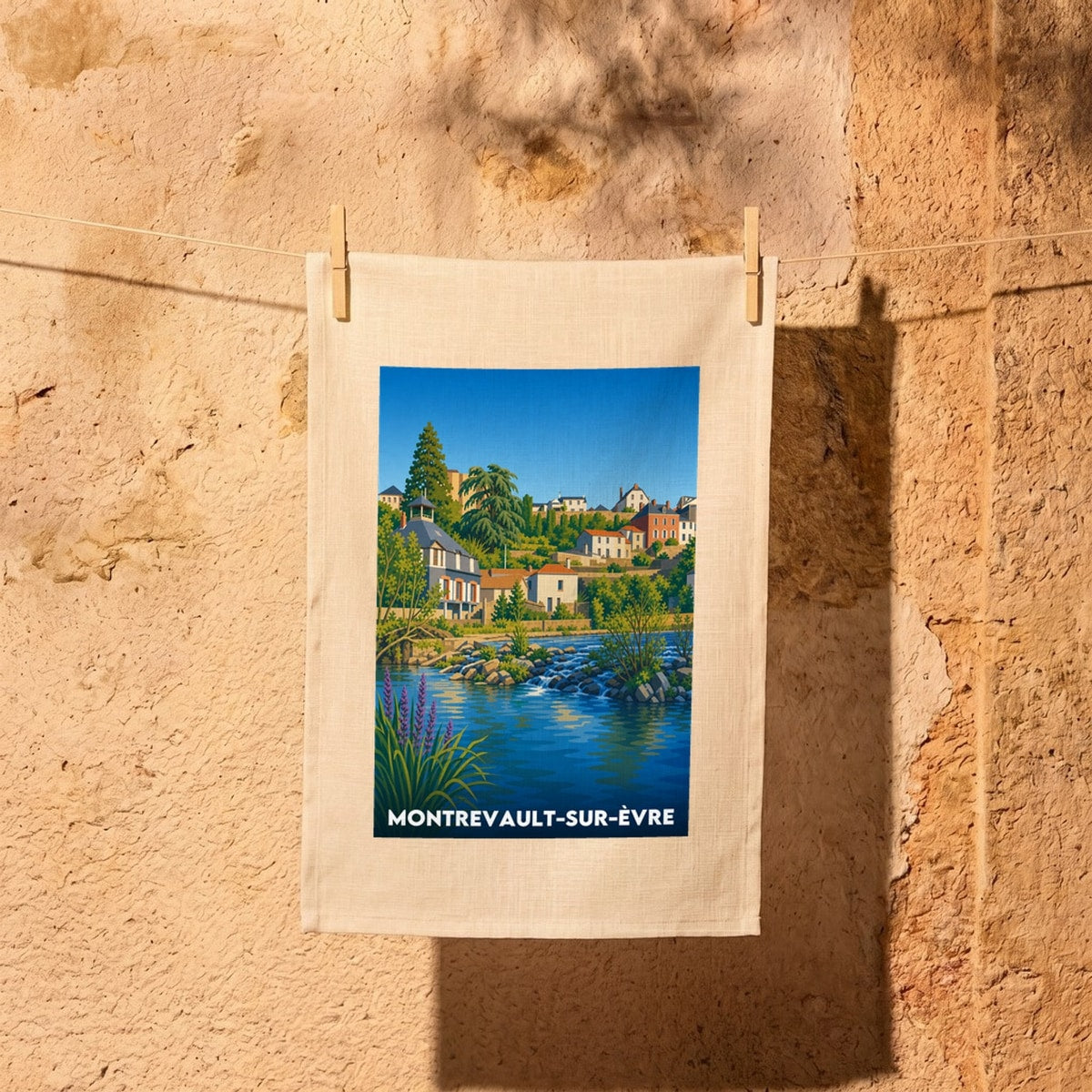 Torchon souvenir de la ville de Montrevault-sur-Èvre avec une illustration stylisée d'un paysage urbain au bord de l'eau.